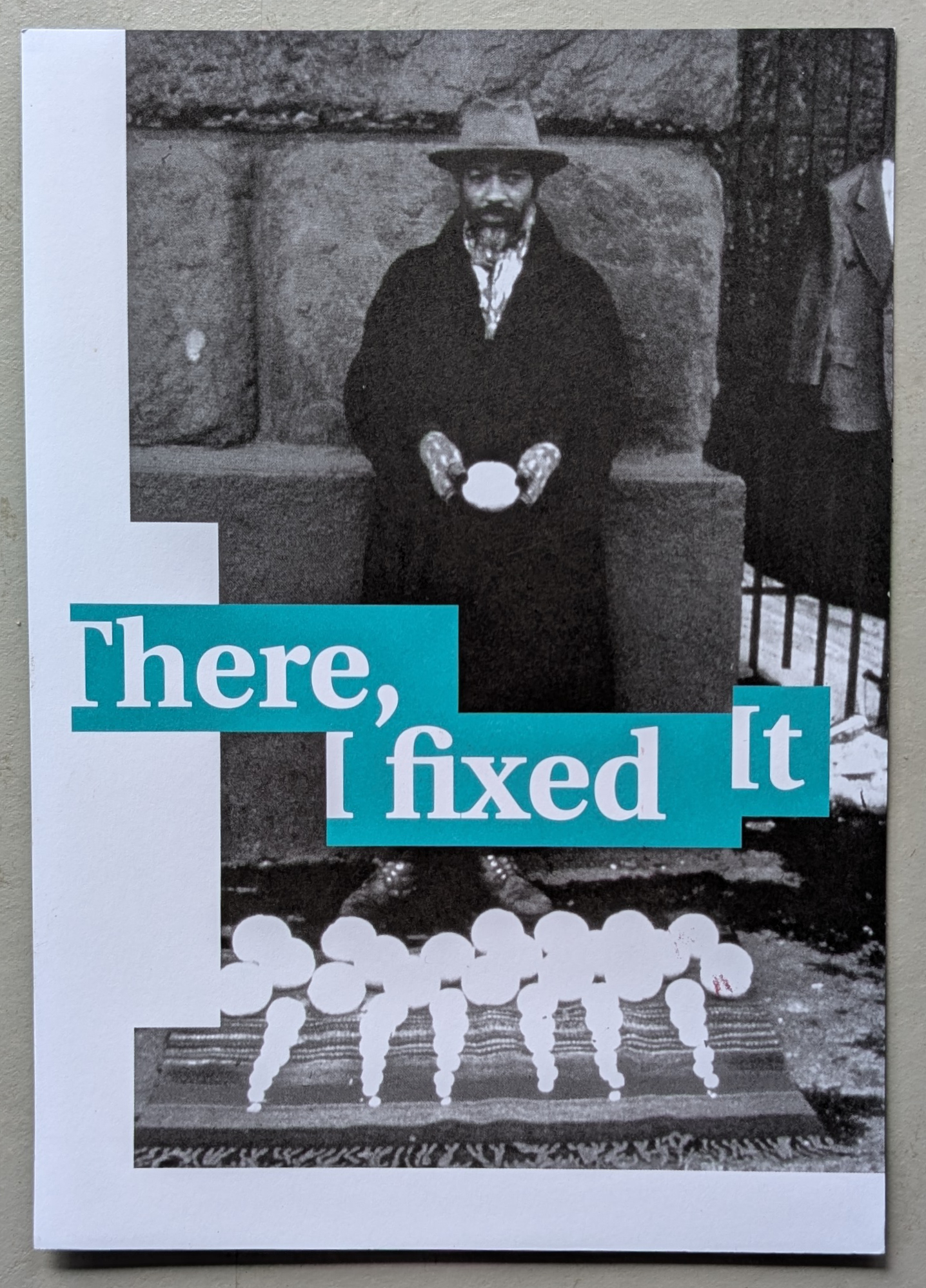 Black and white image of a man wearing a hat and coat, holding a circular object in his hands, with a patterned background and stylized text overlay reading 'There, I fixed It.'