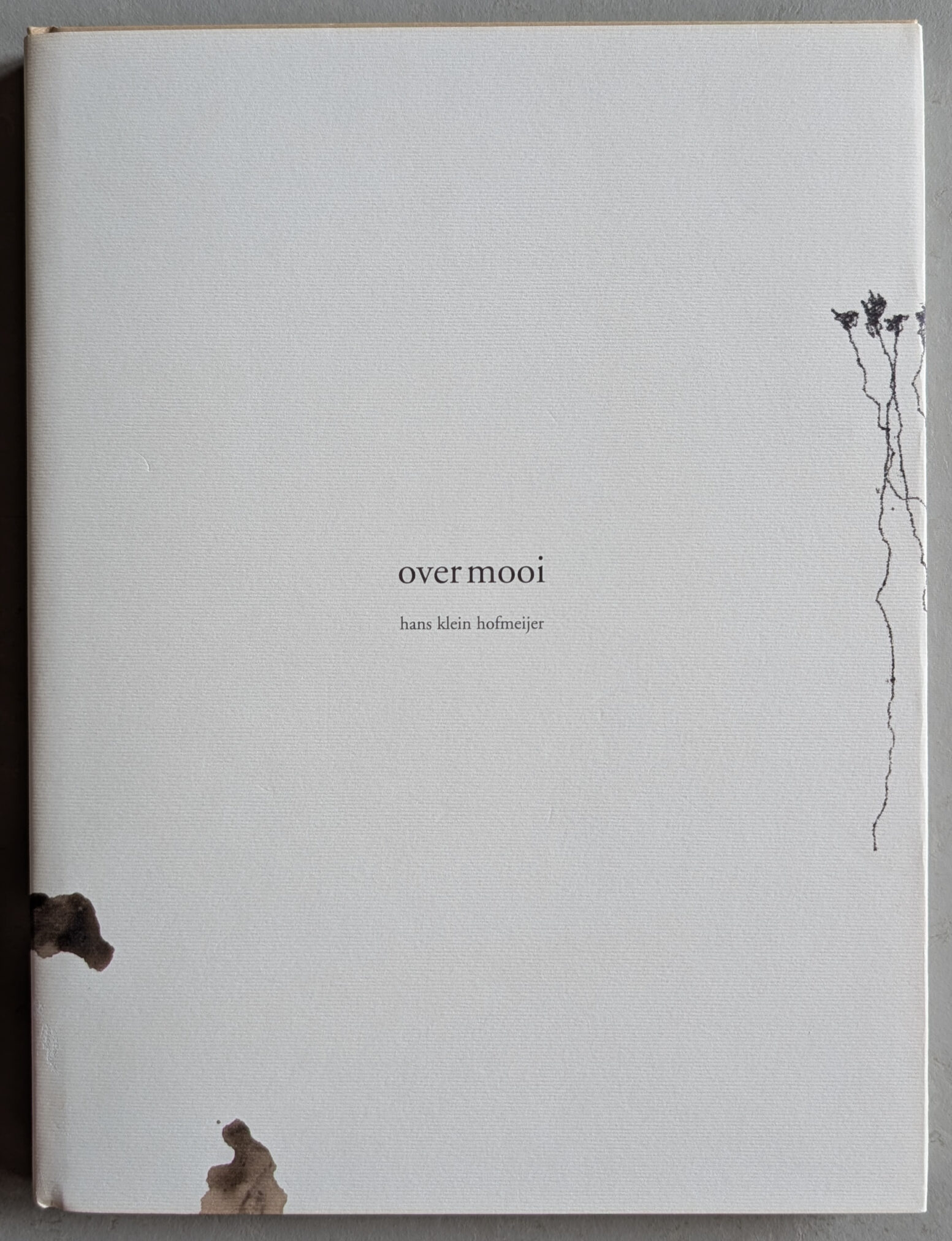 Cover of the book 'over mooi' by Hans Klein Hofmeijer, featuring a minimalist white design with the title and author's name printed in simple black text, along with subtle artistic elements along the edges.