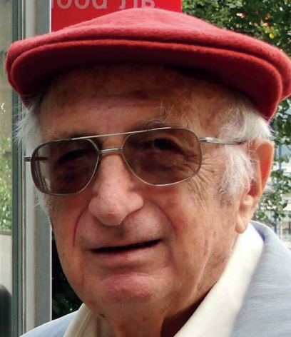 An elderly man with glasses and a red cap, standing outdoors.