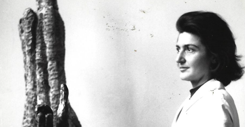 A black and white portrait of a woman in profile, standing next to an abstract sculpture.