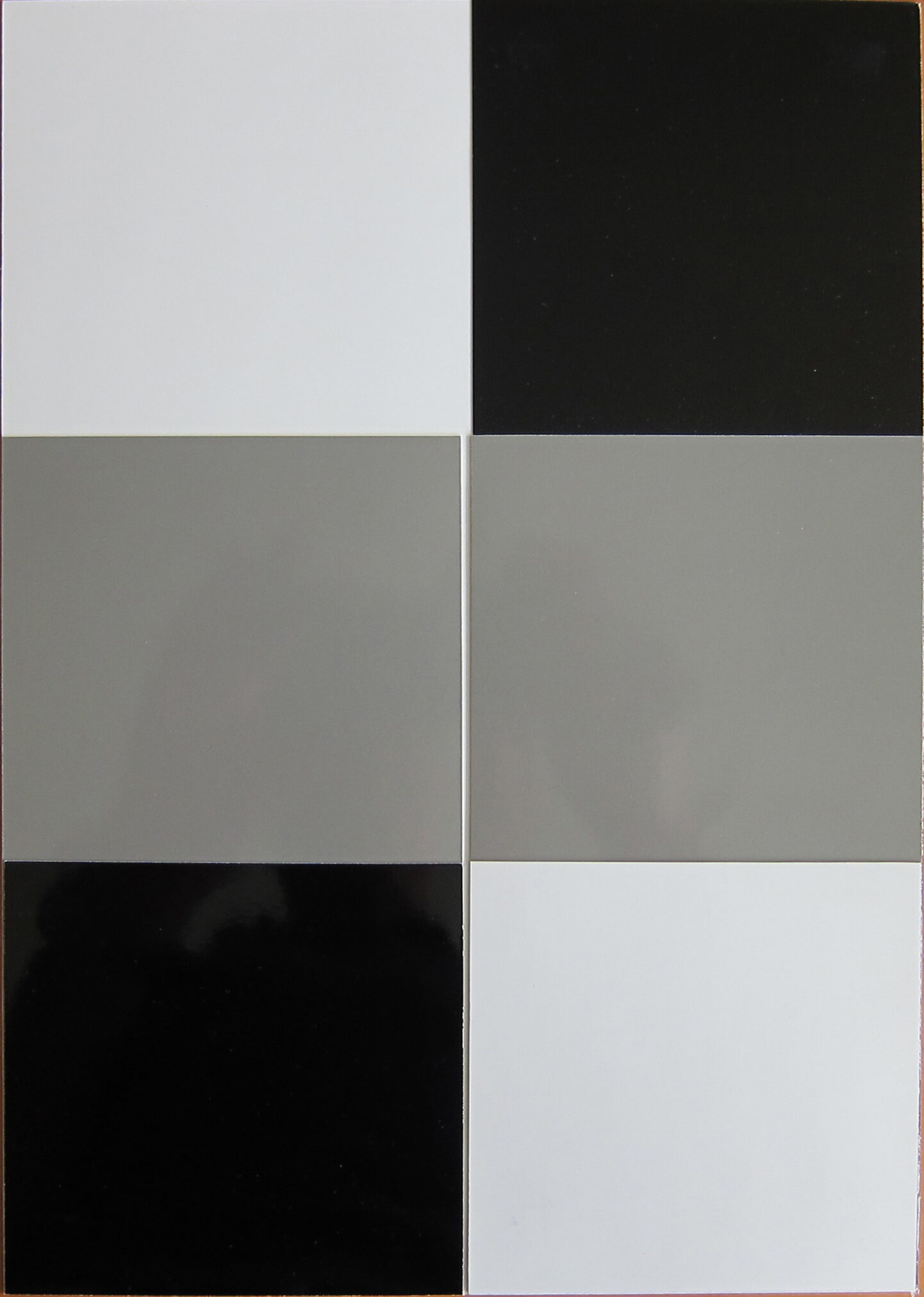 A geometric composition featuring four squares in a grid layout, showcasing shades of white, gray, and black.