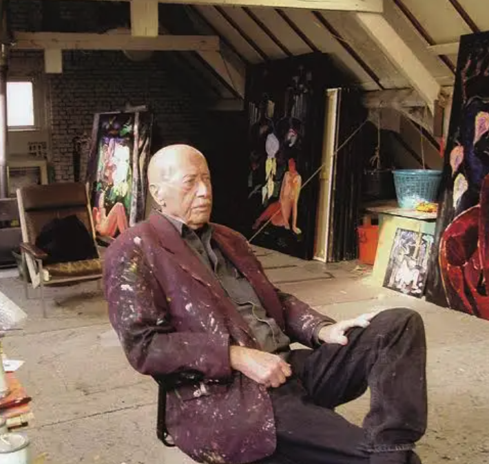 An elderly artist seated in a studio, surrounded by colorful paintings and an artistic ambiance.