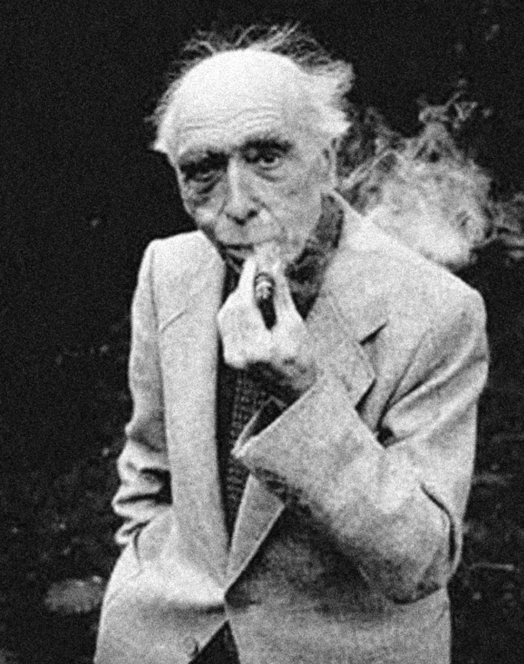 An elderly man wearing a light suit holds a pipe in his mouth, with smoke lingering in the air around him.