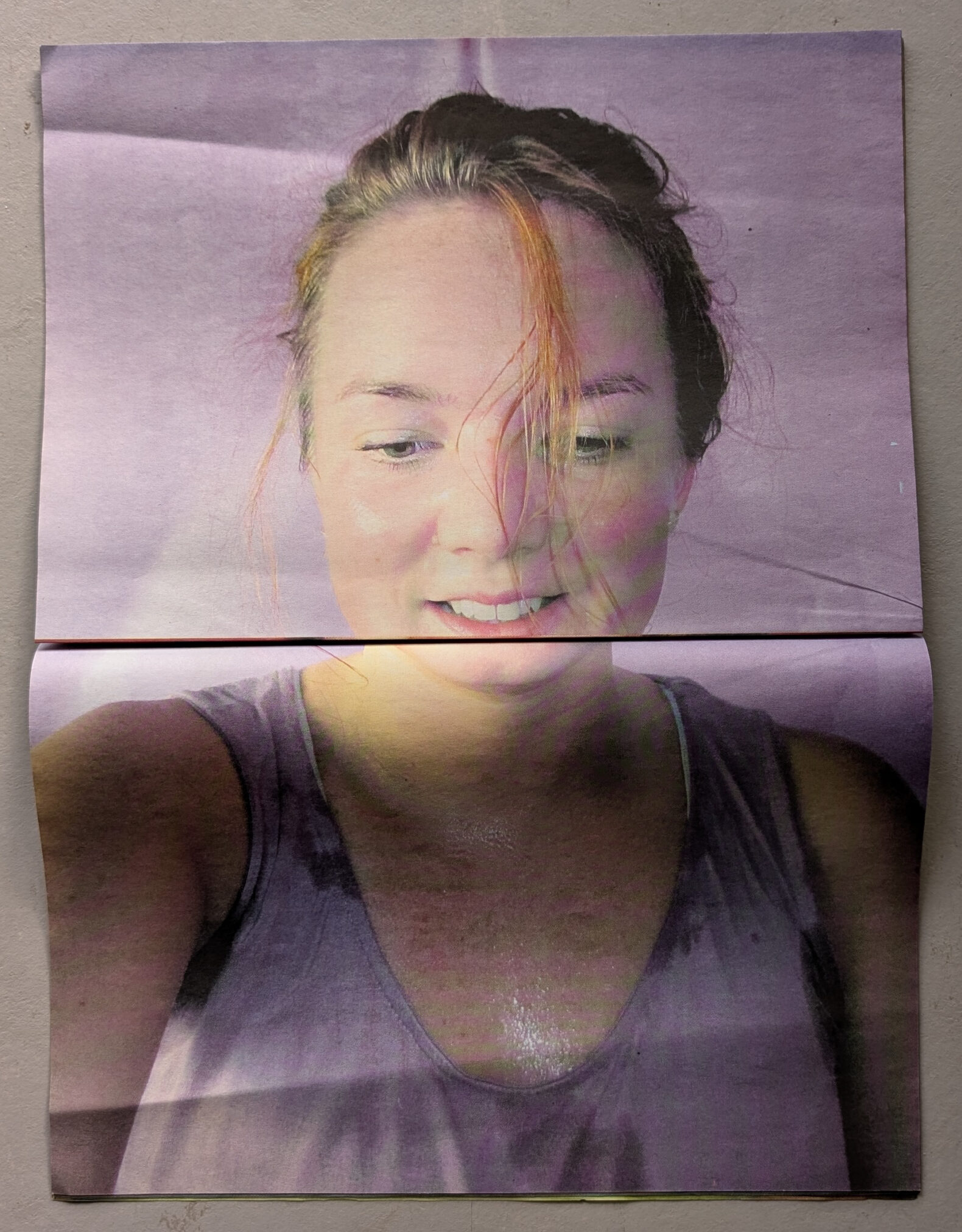 A close-up of a smiling woman with damp hair, showing joy and energy, set against a pastel background. The image appears to be a printed photograph displayed on a flat surface.