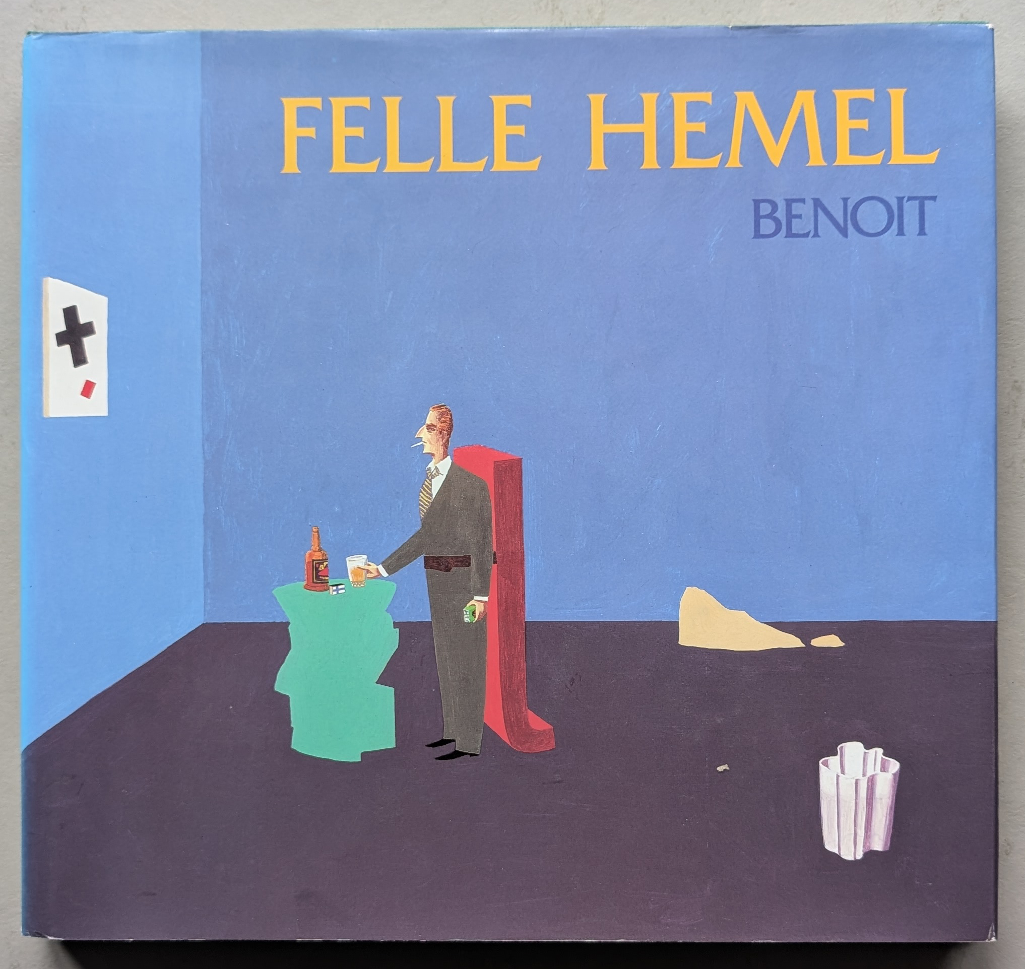 Cover of the book 'FELLE HEMEL' by Benoît, featuring a cartoonish illustration of a man in formal attire standing at a green table with a drink, against a blue background.