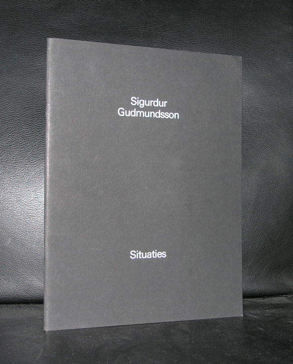 A black book titled 'Situaties' by Sigurdur Gudmundsson, featuring white text on the cover, placed on a black surface.