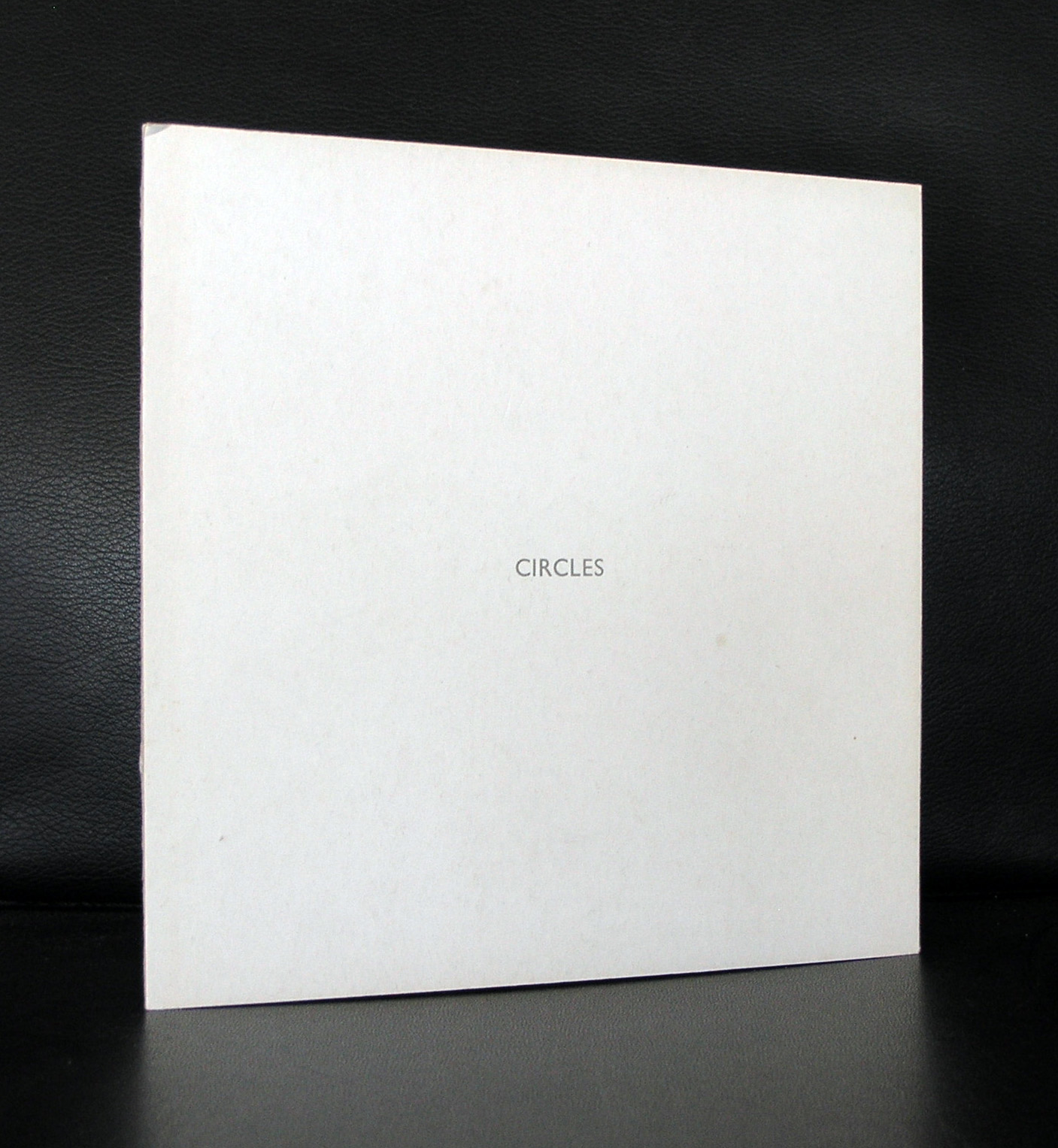 A minimalist book cover titled 'CIRCLES' resting on a dark surface.