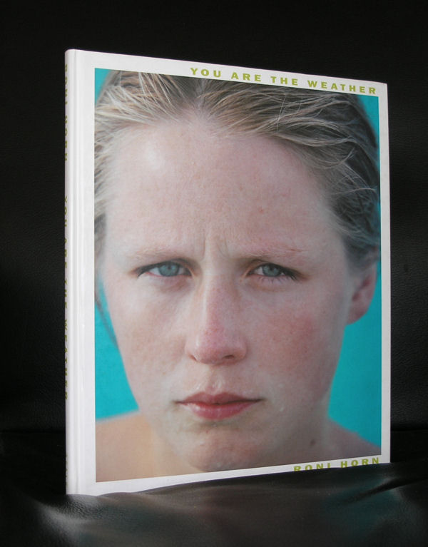 A close-up image of a book cover titled 'You Are the Weather' by Roni Horn, featuring a portrait of a woman with wet hair and a serious expression against a turquoise background.