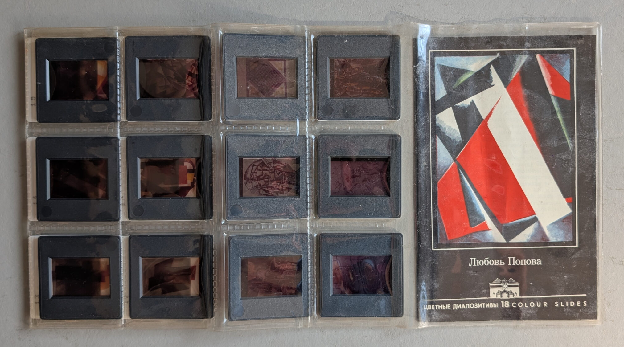 A collection of color slides featuring artworks by Lyubov Popova, displayed in a plastic slide holder, with a cover showcasing abstract geometric designs in red, black, and blue.