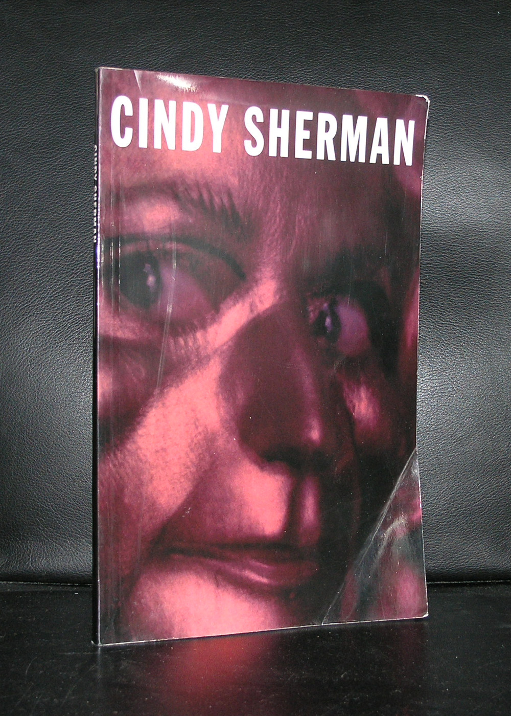 A close-up of a book cover featuring the title 'CINDY SHERMAN' with a dark, abstract image resembling a face in shades of red and black.