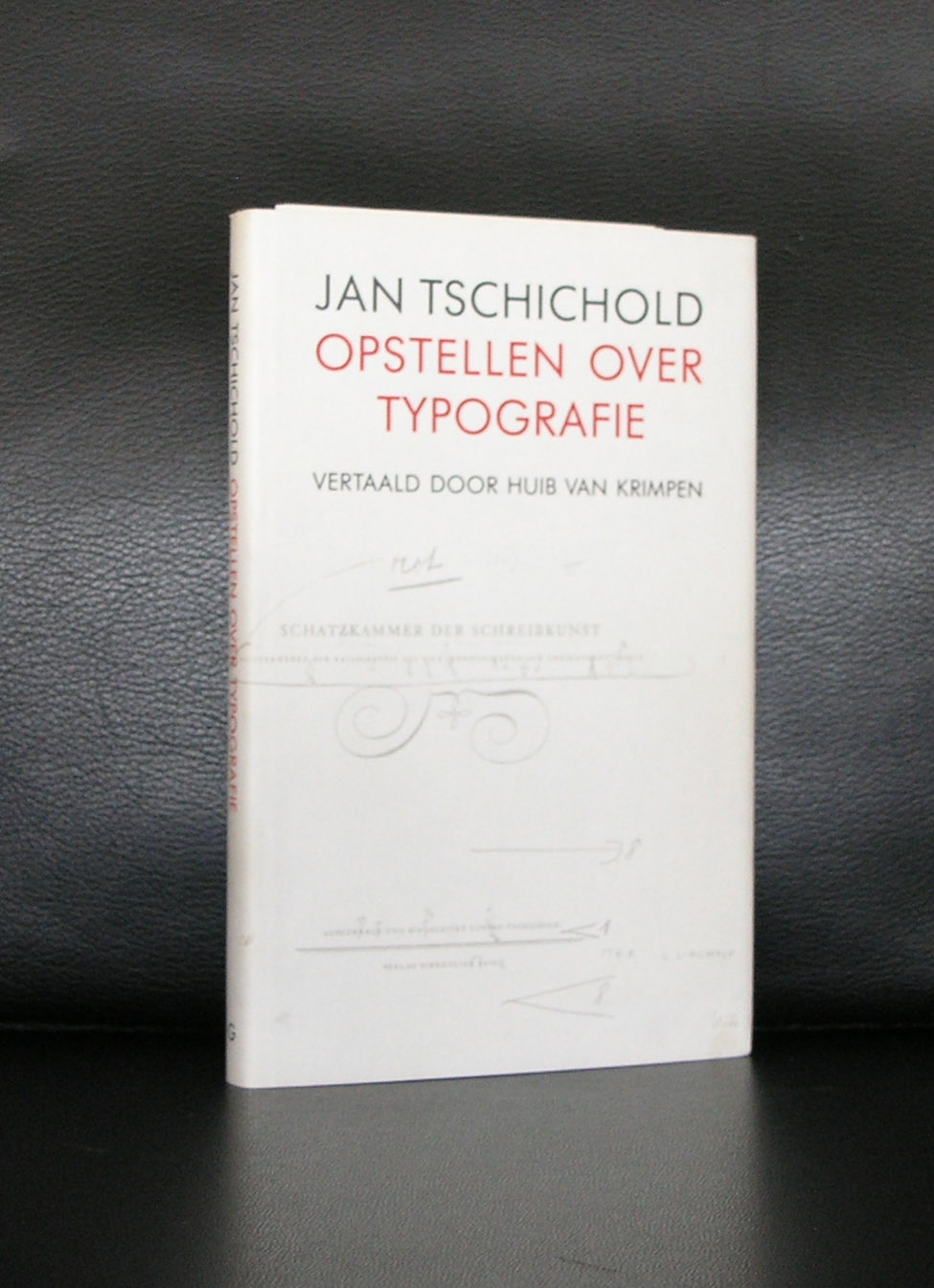 A book cover titled 'Jan Tschichold Opstellen over Typografie' translated by Huib van Krimpen, featuring a minimalist design with red and green text on a white background.