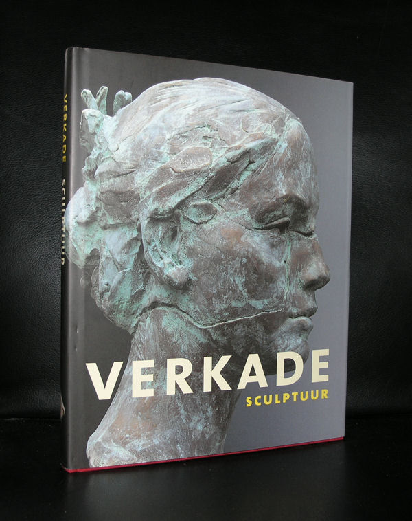 A close-up of a bronze sculpture by Kees Verkade, featuring a female head with intricate details highlighting the texture and expression of the figure.