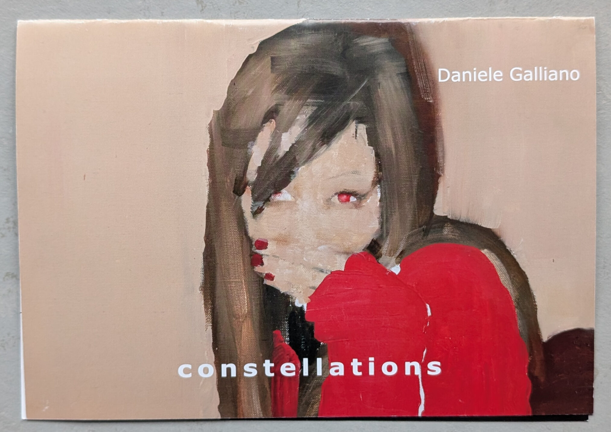 Artistic representation of a woman with long hair and red clothing, covering her face with one hand, featuring the text 'constellations' and the name 'Daniele Galliano'.